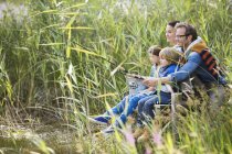 Família pesca juntos em grama alta — Fotografia de Stock