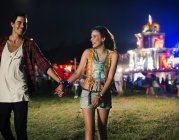 Couple holding hands and leaving music festival — Stock Photo