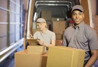 Delivery people loading boxes into van — Stock Photo
