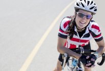Ciclista feminino sorrindo na estrada rural — Fotografia de Stock