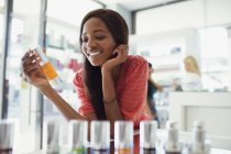 Woman examining skincare product in drugstore — Stock Photo