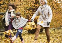 Three generations of women playing in autumn leaves — Stock Photo