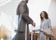 Smiling businesswoman talking to businessman in airport — Stock Photo