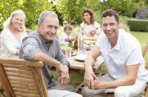 Glückliche Familie lächelt zusammen am Tisch im Garten — Stockfoto