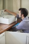 Encanador caucasiano hábil trabalhando na pia do banheiro — Fotografia de Stock