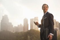 Businessman using cell phone in urban park — Stock Photo