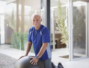 Homem mais velho usando bola de exercício em casa — Fotografia de Stock