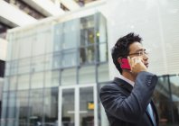Бизнесмен разговаривает по мобильному телефону за пределами офисного здания — стоковое фото