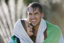 Happy couple wrapped in towel outdoors — Stock Photo