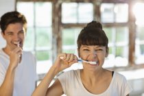 Young happy couple brushing teeth together — Stock Photo