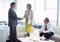 Business people shaking hands in office lobby area — Stock Photo