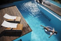 Donna galleggiante su anello gonfiabile in piscina di lusso — Foto stock
