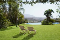 Lawn chairs in grass overlooking swimming pool — Stock Photo