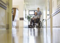 Infermiera con ruote paziente anziano in ospedale — Foto stock