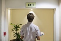 Uomo d'affari che esamina il segno di uscita in ufficio — Foto stock