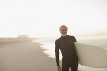 Surfista mais velho carregando bordo na praia — Fotografia de Stock