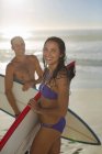 Retrato de casal feliz segurando pranchas de surf na praia — Fotografia de Stock