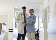 Doctor and nurse using tablet computer in hospital hallway — Stock Photo