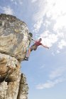 Low angle of climber scaling steep rock face — Stock Photo