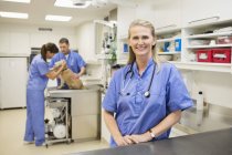 Vétérinaire souriant debout en chirurgie vétérinaire — Photo de stock