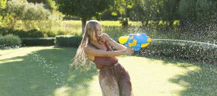 Girl playing with water gun in backyard — Stock Photo
