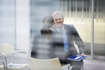 Усміхаючись бізнесмен розмовляти з бізнес-леді на сучасні офісні — стокове фото