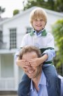 Boy covering father's eyes outdoors — Stock Photo