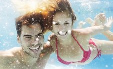 Feliz pareja caucásica nadando en la piscina - foto de stock