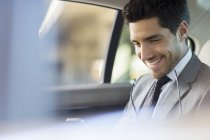 Businessman using cell phone in car back seat — Stock Photo