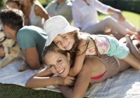 Mother and daughter relaxing in grass with family — Stock Photo