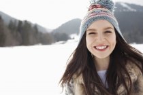 Закрыть портрет счастливой женщины в вязаной шляпе на снежном поле — стоковое фото