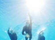Triatletas seguros y fuertes en trajes de neopreno bajo el agua - foto de stock