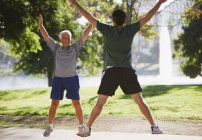 Older men doing jumping jacks outdoors — Stock Photo