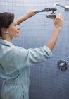 Женщина-сантехник работает над душевой головой в ванной комнате — стоковое фото