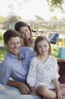 Portrait of smiling family picnicking at lakeside — Stock Photo