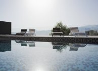 Sol brilhando sobre espreguiçadeiras e piscina — Fotografia de Stock