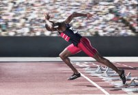 Sprinter taking off from starting block on track — Stock Photo