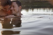 Sonriente pareja nadando en el lago - foto de stock