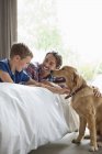 Padre e figlio accarezzano cane in camera da letto — Foto stock