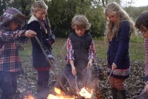 Happy children poking bonfire outdoors — Stock Photo