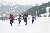 Family running in snowy field — Stock Photo