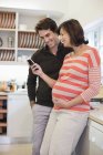 Беременная женщина и парень с помощью мобильного телефона — стоковое фото