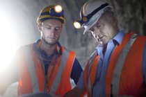 Workers in hard hats talking in tunnel — Stock Photo