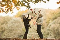 Casal mais velho jogando em folhas de outono — Fotografia de Stock