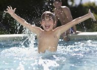 Menino feliz jogando na piscina — Fotografia de Stock
