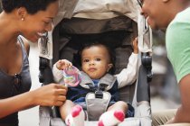 Parents talking to baby in stroller on city street — Stock Photo