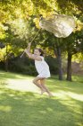 Happy girl running with butterfly net in grass — Stock Photo