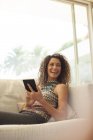 Young attractive Woman using tablet computer on sofa — Stock Photo