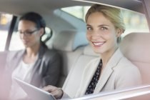 Geschäftsfrau nutzt digitales Tablet auf Rücksitz im Auto — Stockfoto