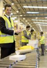 Рабочие проверяют пакеты на конвейерной ленте на складе — стоковое фото